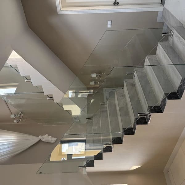 Escada interior branca com guarda em vidro e fixações em aço inoxidável.